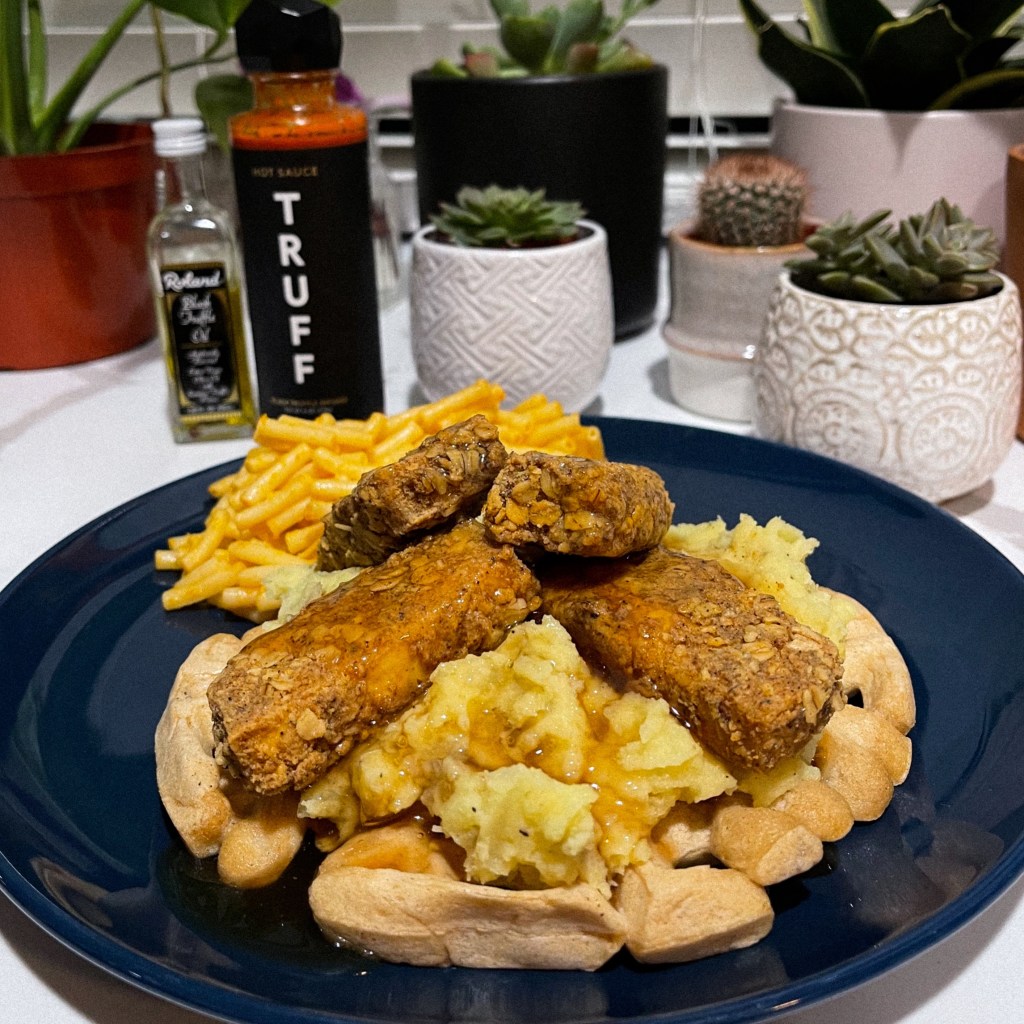a delicious vegan belgium waffle stacked with light & fluffy mashed potatoes and crispy tofu chickn' on top